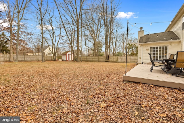 view of yard with a fenced backyard, an outbuilding, a storage unit, a wooden deck, and outdoor dining space