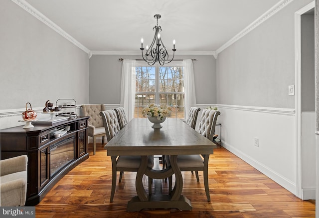 dining area featuring crown molding, a notable chandelier, and light wood-style flooring