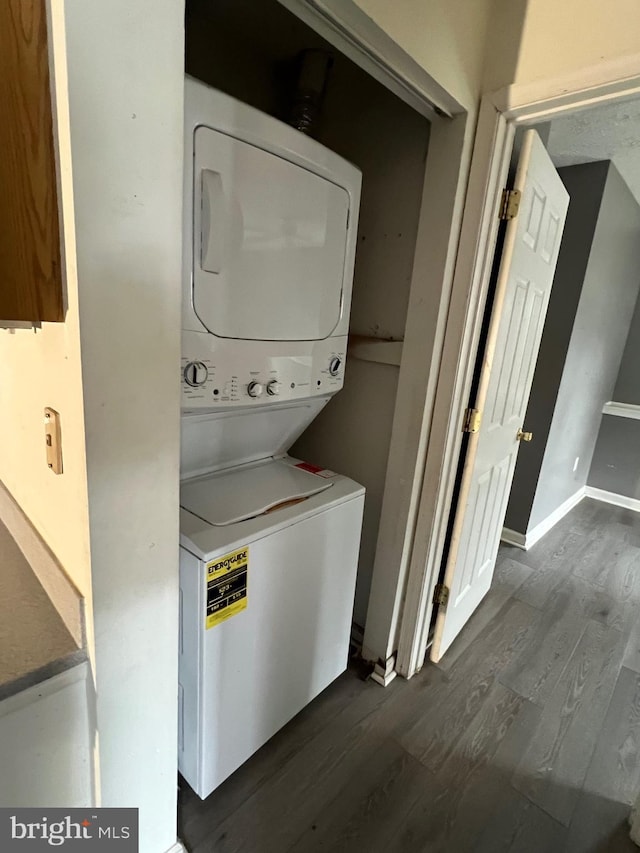 washroom featuring laundry area, dark wood-style flooring, stacked washer and clothes dryer, and baseboards