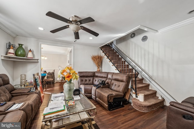 living room with ceiling fan with notable chandelier, ornamental molding, stairway, and wood finished floors