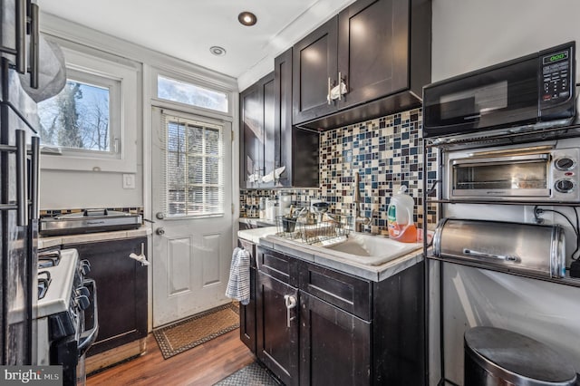 kitchen with black microwave, a toaster, dark wood-type flooring, light countertops, and tasteful backsplash