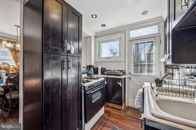 kitchen featuring dark wood-style flooring, recessed lighting, light countertops, ornamental molding, and white gas range oven