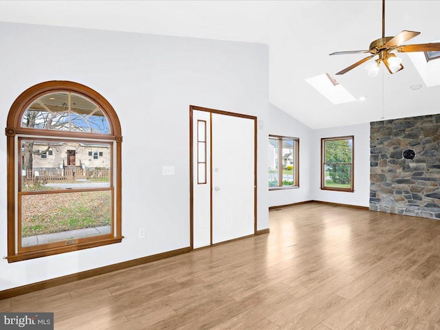 unfurnished living room with high vaulted ceiling, a skylight, ceiling fan, and light wood-style flooring