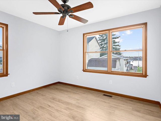 unfurnished room with light wood-style flooring, visible vents, and baseboards