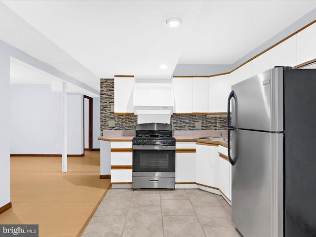 kitchen featuring stainless steel appliances, white cabinets, light countertops, and decorative backsplash