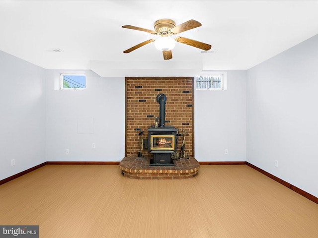 unfurnished living room featuring baseboards, a wood stove, and a healthy amount of sunlight