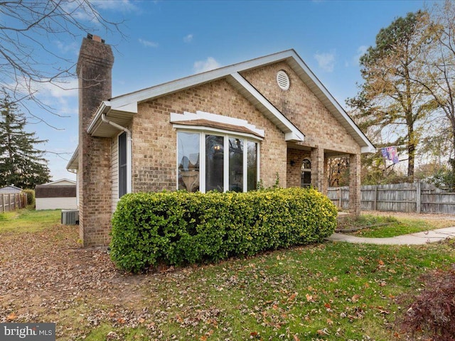 back of house featuring a yard, a chimney, fence, and brick siding