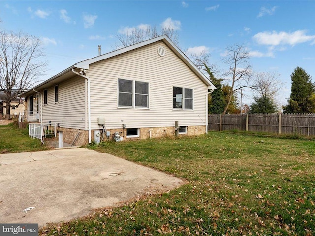 view of side of property featuring a patio, fence, and a lawn