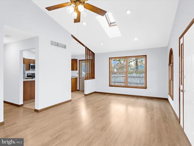 unfurnished living room featuring light wood finished floors, baseboards, a skylight, and visible vents