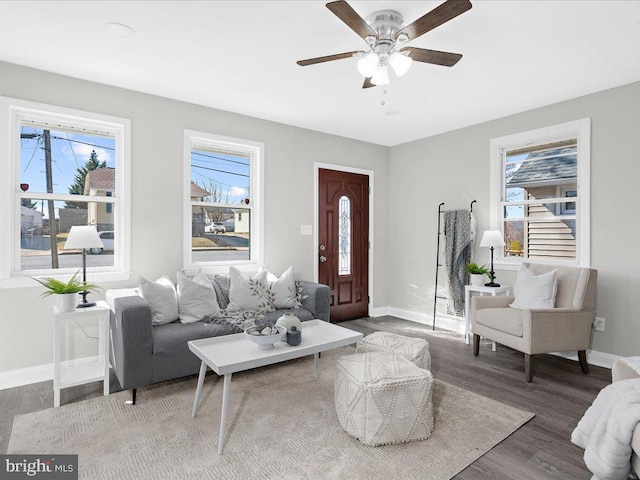 living room featuring dark wood-type flooring, a ceiling fan, and baseboards