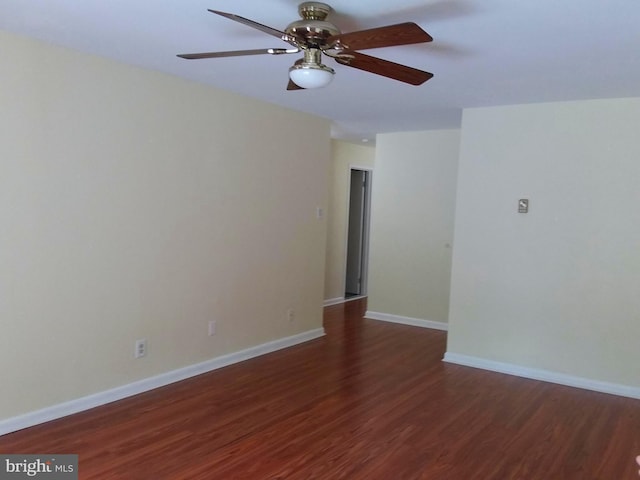 unfurnished room with dark wood finished floors, a ceiling fan, and baseboards