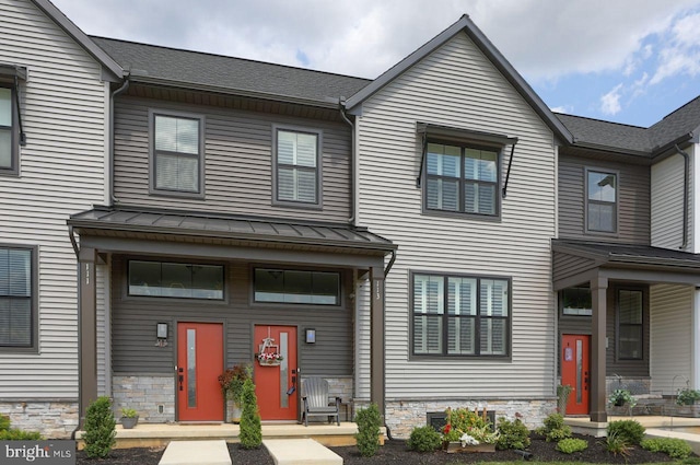 townhome / multi-family property featuring a standing seam roof, stone siding, and metal roof