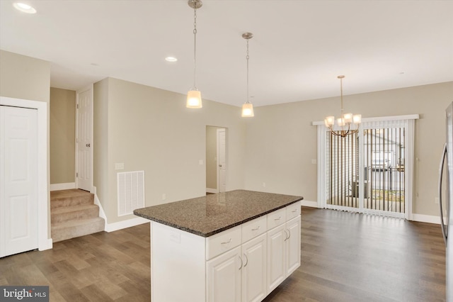 kitchen with dark wood-style floors, a center island, visible vents, white cabinetry, and baseboards