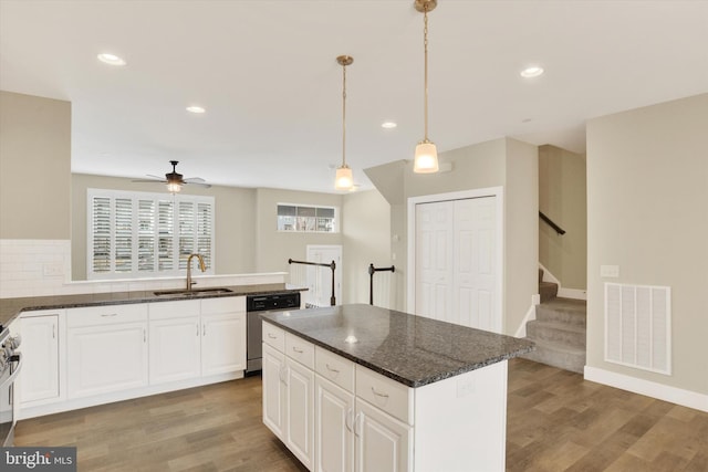 kitchen featuring stainless steel dishwasher, light wood-style flooring, a sink, and visible vents