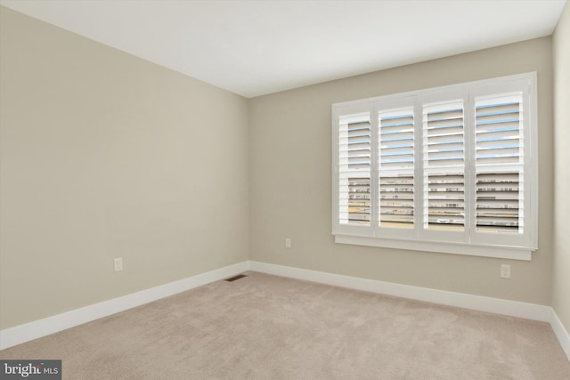 empty room featuring carpet, visible vents, and baseboards