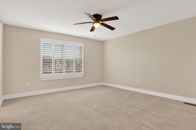 carpeted empty room featuring baseboards, visible vents, and a ceiling fan