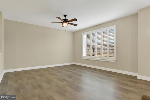 spare room featuring baseboards, visible vents, ceiling fan, and wood finished floors