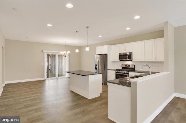 kitchen featuring appliances with stainless steel finishes, tasteful backsplash, a sink, and wood finished floors