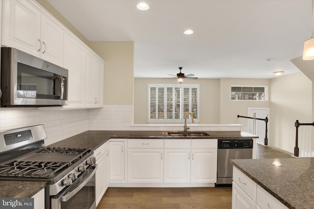 kitchen featuring appliances with stainless steel finishes, white cabinets, a sink, and a peninsula