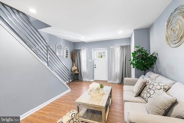 living area with recessed lighting, wood finished floors, baseboards, and stairs