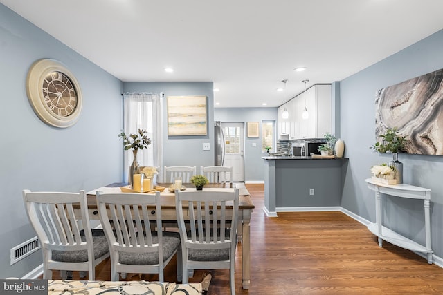 dining room featuring visible vents, baseboards, wood finished floors, and recessed lighting