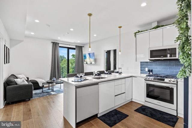 kitchen with open floor plan, hanging light fixtures, appliances with stainless steel finishes, and a peninsula