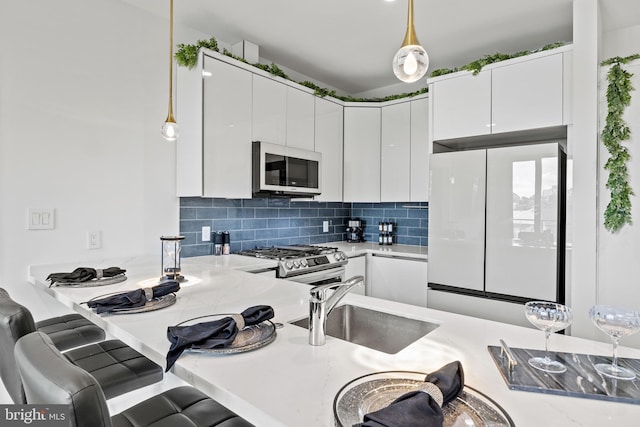 kitchen featuring white appliances, white cabinets, light countertops, modern cabinets, and decorative light fixtures