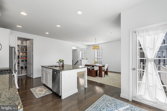 kitchen featuring dark wood-style floors, a breakfast bar, a sink, dark stone counters, and dishwasher