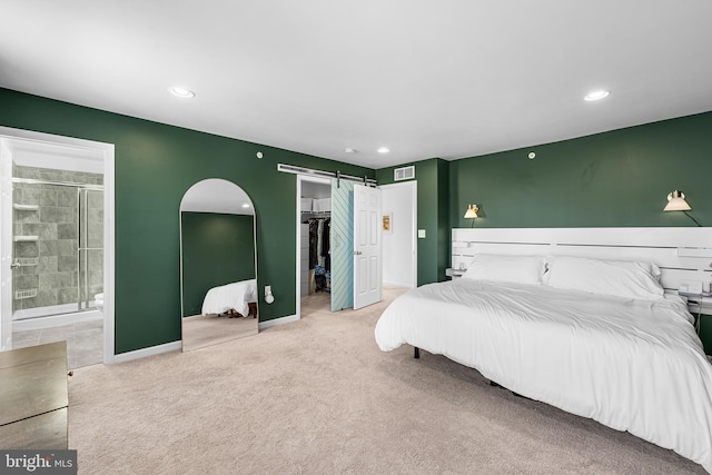 carpeted bedroom featuring ensuite bathroom, a barn door, recessed lighting, visible vents, and a spacious closet