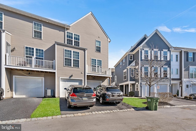 view of property with driveway, an attached garage, and central air condition unit