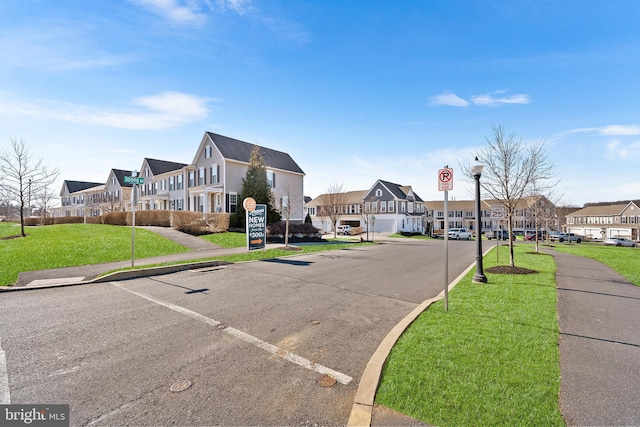 view of street with sidewalks, curbs, a residential view, street lighting, and traffic signs