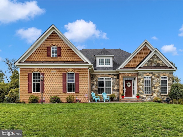 traditional-style home featuring a front yard, stone siding, brick siding, and a standing seam roof