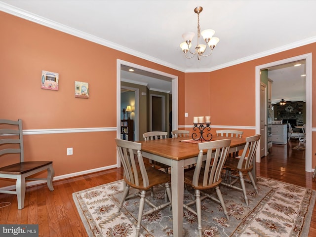 dining space with ornamental molding, wood-type flooring, baseboards, and ceiling fan with notable chandelier