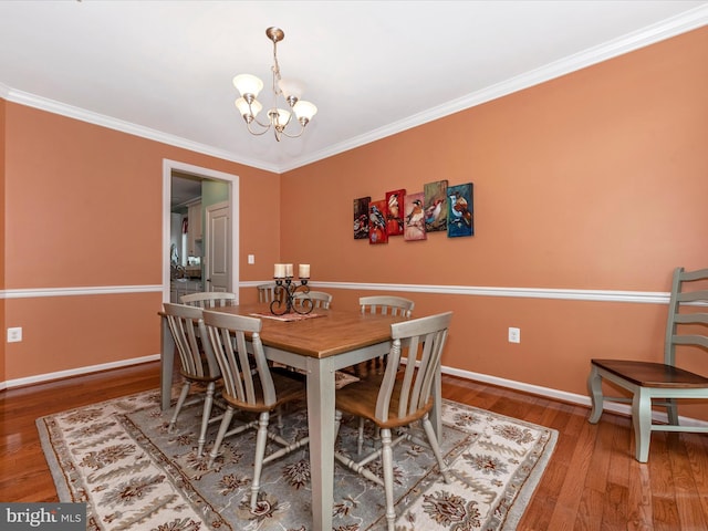 dining room with wood finished floors, crown molding, baseboards, and an inviting chandelier