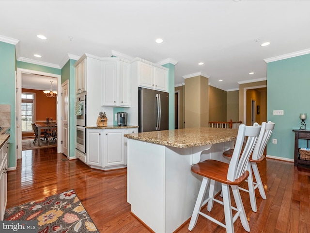 kitchen with a center island, white cabinetry, wood-type flooring, and freestanding refrigerator