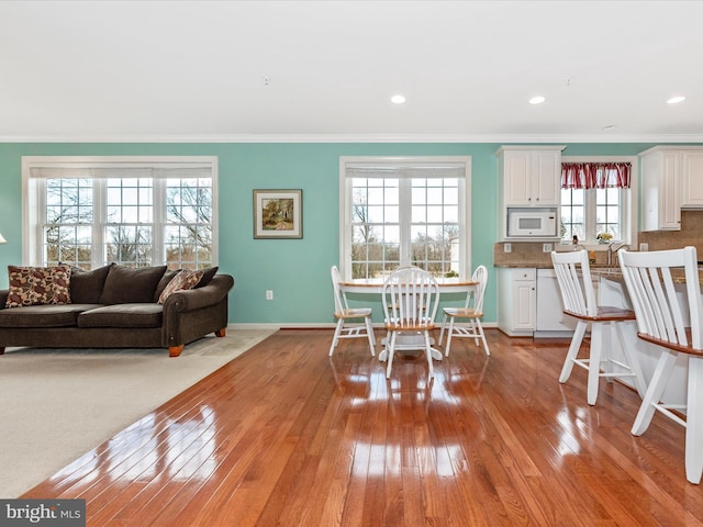 dining space featuring light wood-type flooring, baseboards, crown molding, and recessed lighting