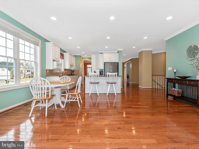 dining area with plenty of natural light, baseboards, and light wood-style flooring