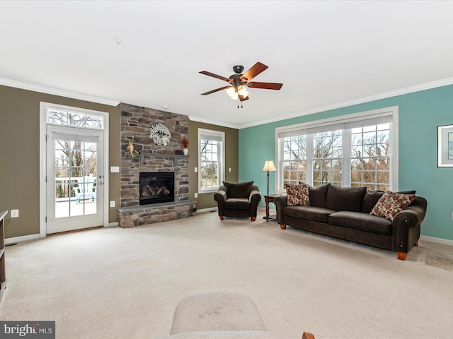 carpeted living area with ornamental molding, a stone fireplace, baseboards, and a ceiling fan