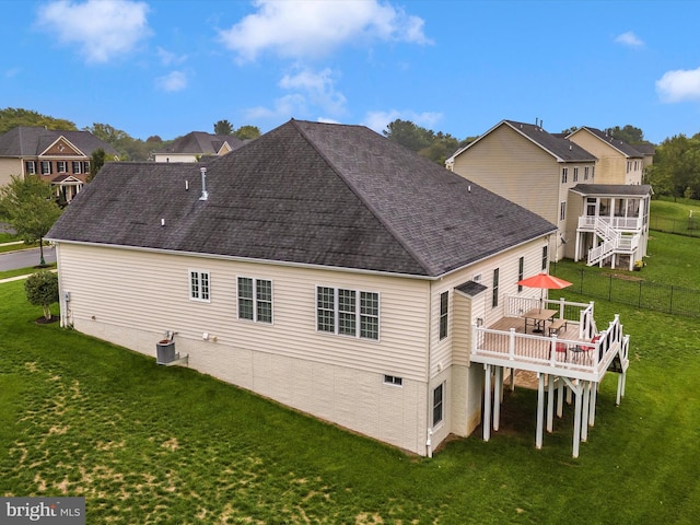 rear view of house featuring a shingled roof, a residential view, a yard, and a deck