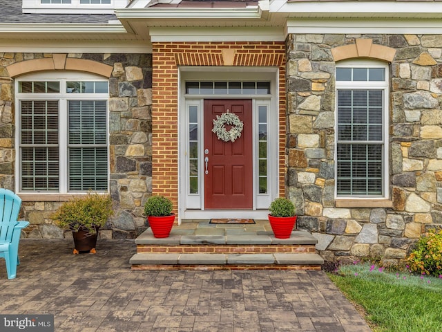 view of exterior entry featuring stone siding and brick siding