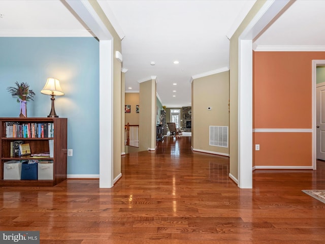 entrance foyer with baseboards, visible vents, wood finished floors, and ornamental molding