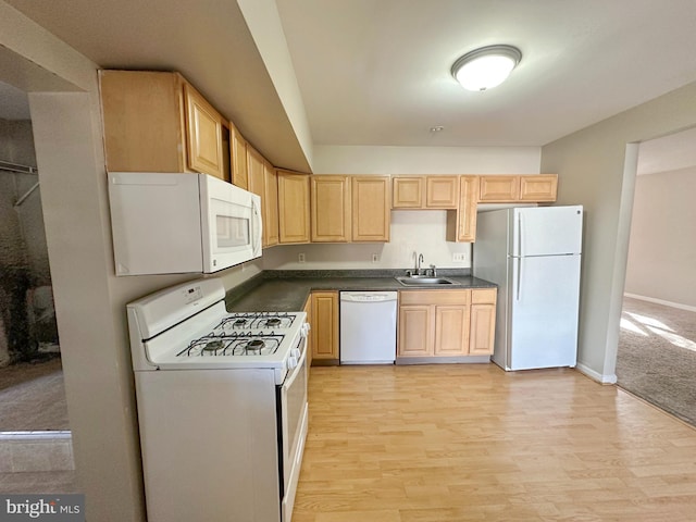 kitchen with light brown cabinets, white appliances, dark countertops, and a sink