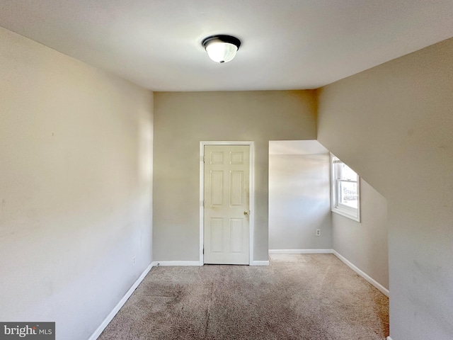 spare room featuring light colored carpet and baseboards