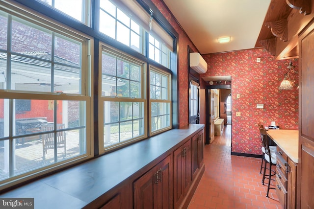 hallway featuring baseboards, an AC wall unit, brick floor, and wallpapered walls