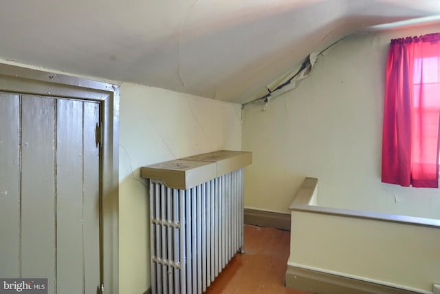 hallway with vaulted ceiling, wood finished floors, and an upstairs landing