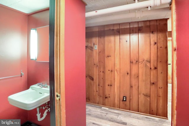 bathroom featuring a sink, wooden walls, and wood finished floors