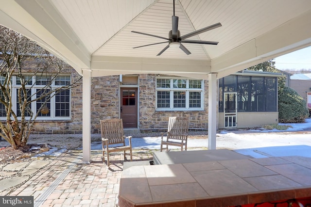 view of patio / terrace with a ceiling fan and a sunroom