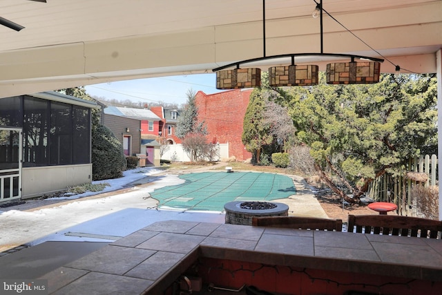 view of pool with a patio, a fire pit, fence, a sunroom, and a fenced in pool