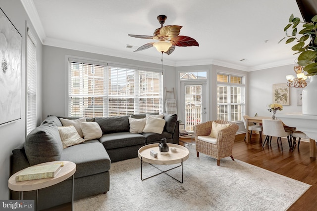 living room featuring ceiling fan with notable chandelier, wood finished floors, visible vents, and crown molding