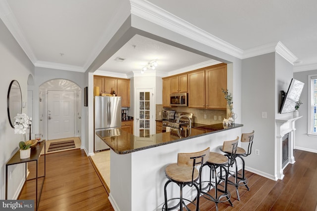 kitchen featuring dark stone counters, stainless steel appliances, hardwood / wood-style floors, and a peninsula